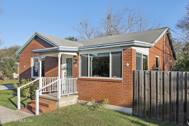 bungalow featuring fence and brick siding