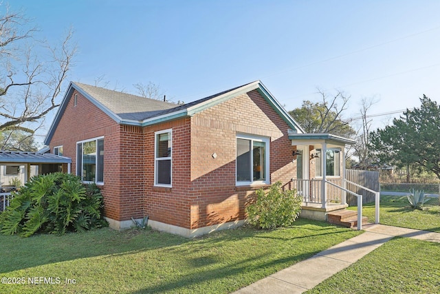 view of front of property with a front lawn, brick siding, and a shingled roof