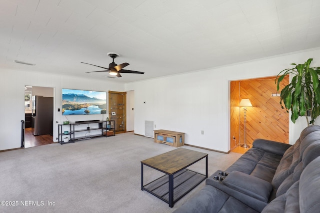 living area with a ceiling fan, wooden walls, carpet, and visible vents