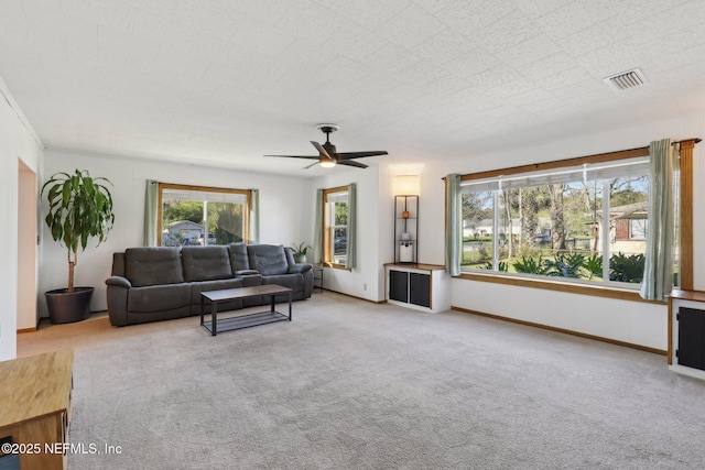 living area with a ceiling fan, visible vents, carpet floors, and baseboards