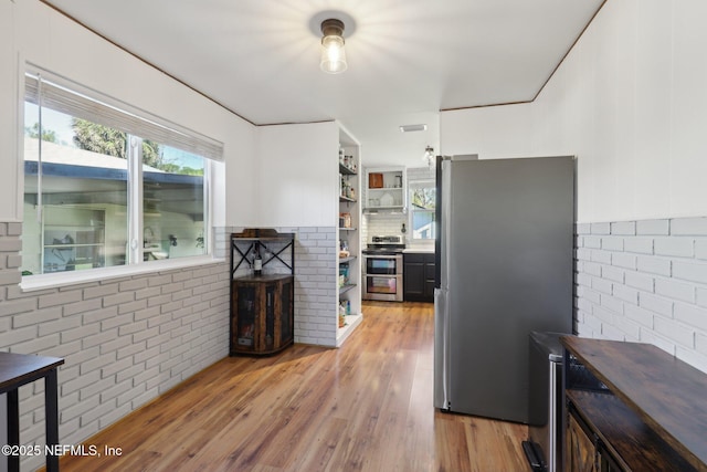 kitchen with visible vents, brick wall, open shelves, light wood-style floors, and appliances with stainless steel finishes