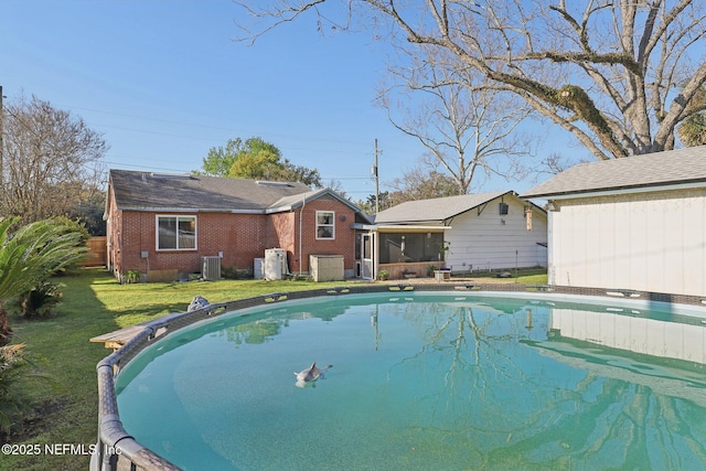 pool with cooling unit, a yard, and a sunroom