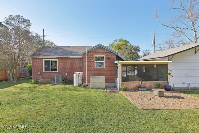 rear view of house featuring brick siding, fence, central AC, a yard, and a sunroom