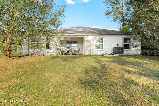 back of property with central air condition unit, stucco siding, and a yard