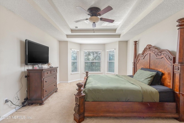 bedroom with light carpet, a textured ceiling, a raised ceiling, and baseboards