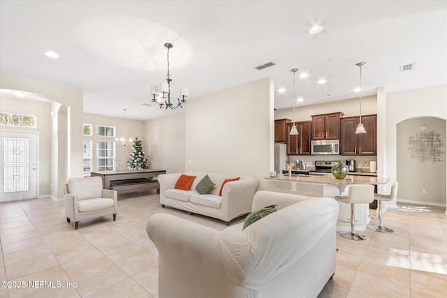 living room featuring an inviting chandelier, visible vents, arched walkways, and recessed lighting