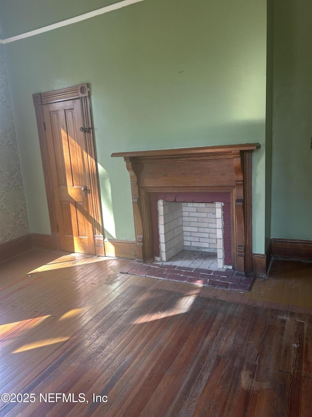 room details featuring a brick fireplace, baseboards, and wood finished floors