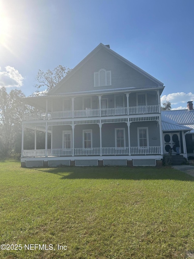 view of front of home featuring a standing seam roof, metal roof, a porch, and a front yard