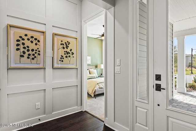 foyer with ornate columns, ceiling fan, dark wood finished floors, and a decorative wall