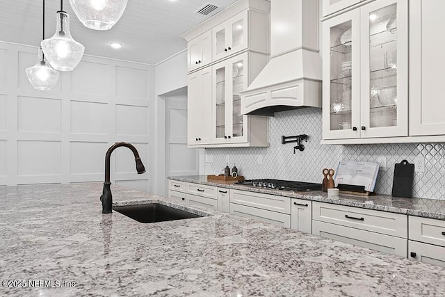 kitchen with stainless steel gas stovetop, visible vents, a decorative wall, and a sink