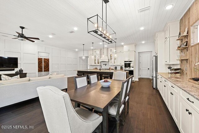 dining space featuring dark wood finished floors, wooden ceiling, a decorative wall, and recessed lighting