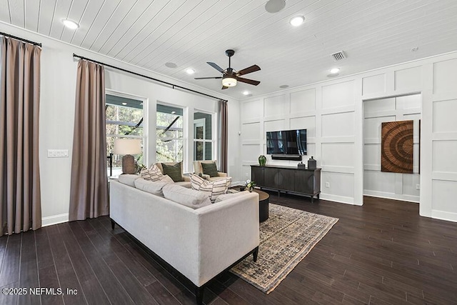 living room featuring dark wood-style flooring, wooden ceiling, a ceiling fan, and a decorative wall