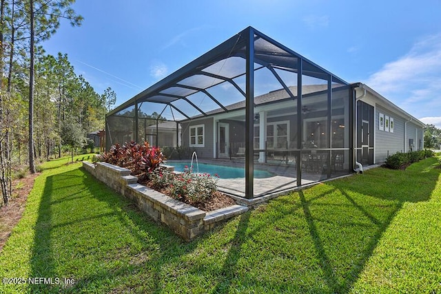 pool with a ceiling fan, a patio area, glass enclosure, and a lawn