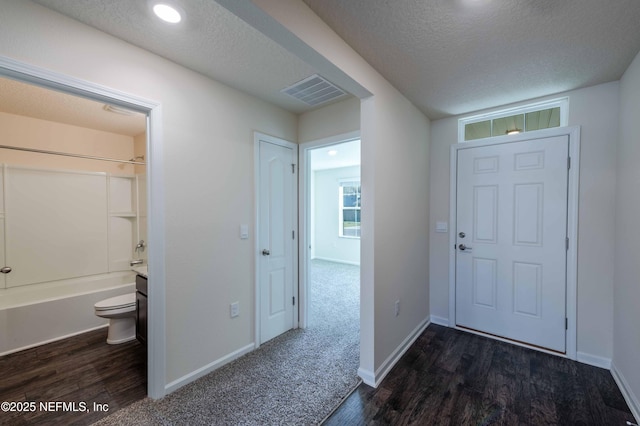 entryway featuring a textured ceiling, dark wood finished floors, and visible vents