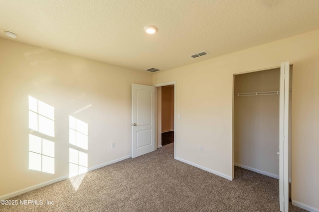 unfurnished bedroom featuring carpet, visible vents, and a textured ceiling