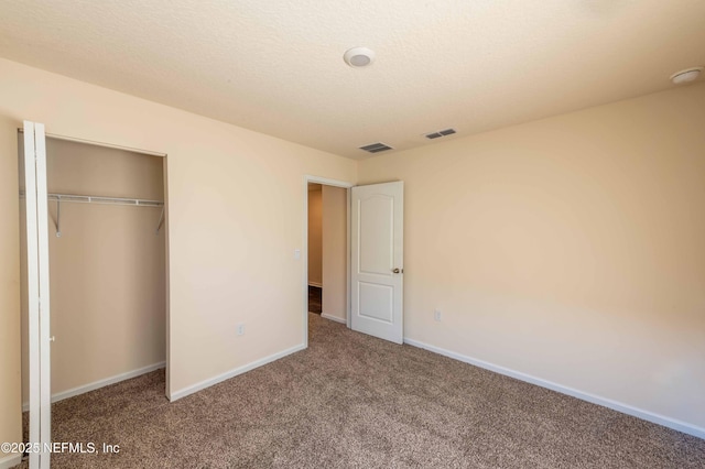 unfurnished bedroom with baseboards, a textured ceiling, visible vents, and carpet flooring