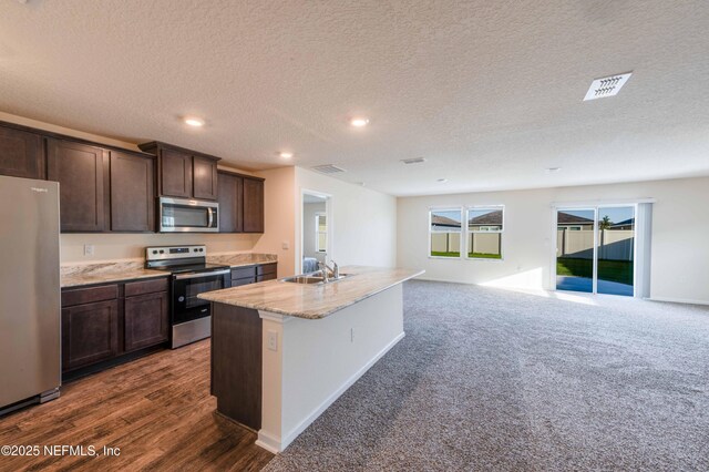 kitchen with stainless steel appliances, a sink, visible vents, open floor plan, and dark brown cabinets