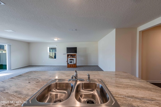 kitchen featuring carpet floors, a sink, visible vents, baseboards, and open floor plan