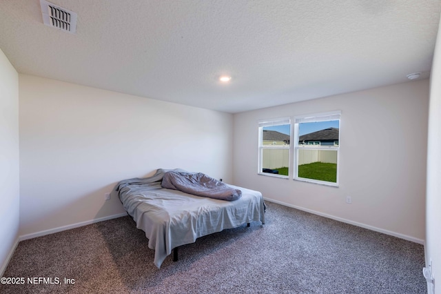 bedroom with carpet, visible vents, a textured ceiling, and baseboards