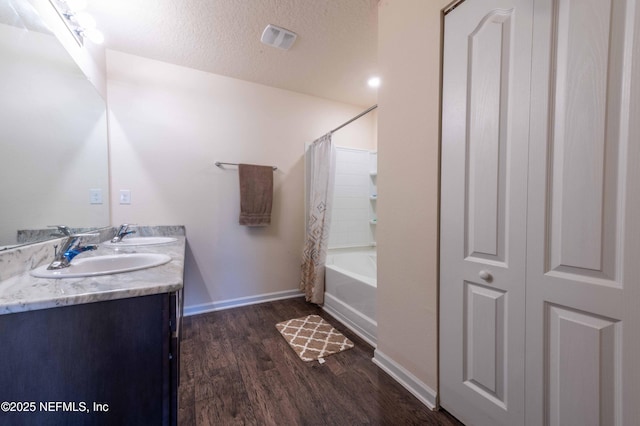 bathroom featuring a sink, a textured ceiling, baseboards, and wood finished floors