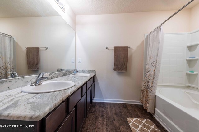 bathroom with a textured ceiling, baseboards, a sink, and wood finished floors