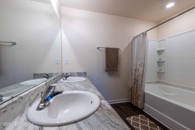 bathroom featuring a textured ceiling, wood finished floors, and a sink