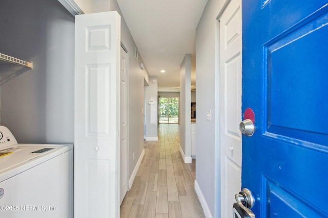 clothes washing area featuring laundry area, baseboards, washer / clothes dryer, and light wood finished floors