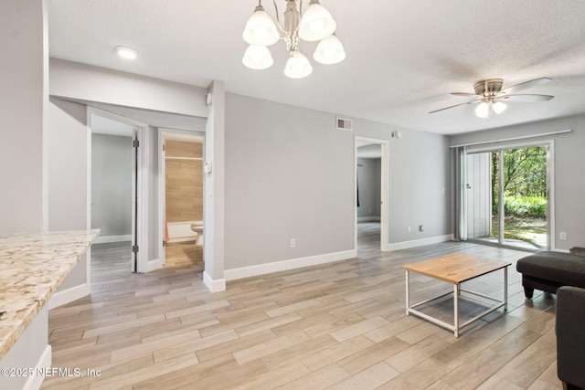 living area with baseboards, a textured ceiling, and wood finish floors