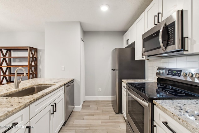 kitchen featuring a sink, white cabinets, appliances with stainless steel finishes, decorative backsplash, and wood tiled floor