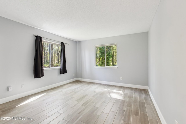 unfurnished room with light wood-style floors, baseboards, and a wealth of natural light