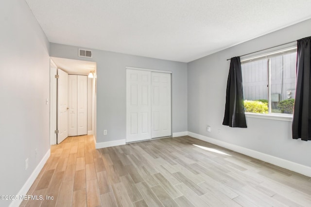 unfurnished bedroom with light wood-style flooring, visible vents, and baseboards