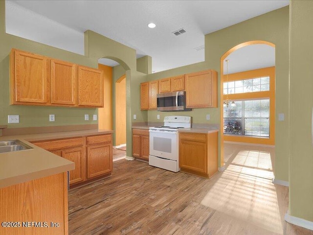 kitchen featuring arched walkways, visible vents, light countertops, white range with electric stovetop, and stainless steel microwave