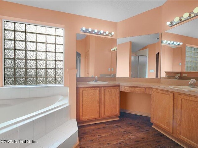 bathroom featuring wood finished floors, a garden tub, a sink, and double vanity