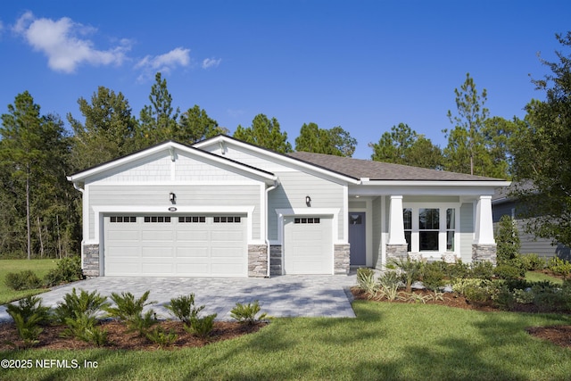 view of front facade featuring a garage, decorative driveway, a front lawn, and stone siding