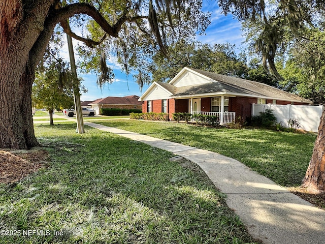 ranch-style home featuring covered porch, a front yard, fence, and brick siding