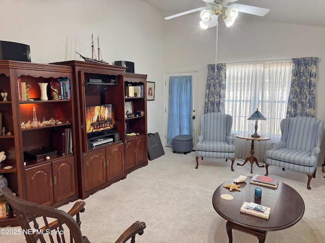 living area featuring light carpet, high vaulted ceiling, and a ceiling fan