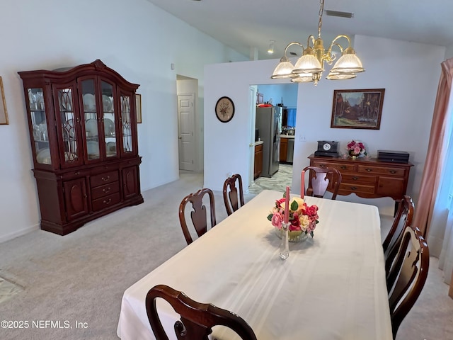 dining area with a chandelier, visible vents, vaulted ceiling, and light colored carpet