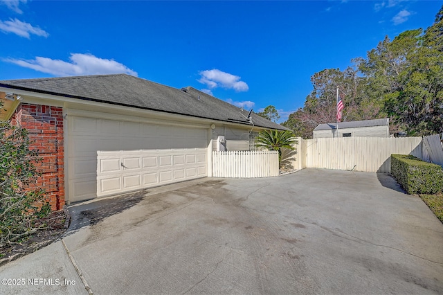 view of property exterior featuring driveway, brick siding, a shingled roof, and fence