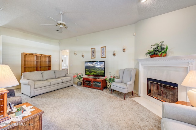 living area with a textured ceiling, a fireplace with flush hearth, ceiling fan, and carpet flooring