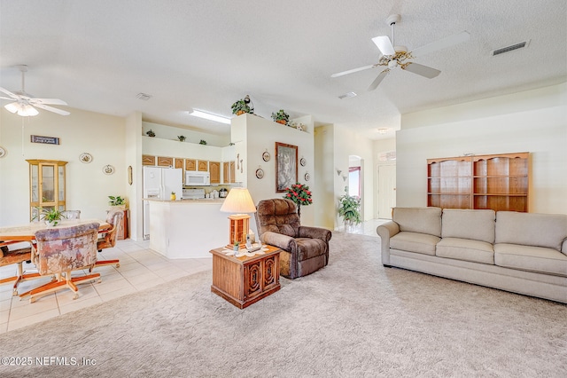 living room featuring a ceiling fan, visible vents, a textured ceiling, and light tile patterned floors