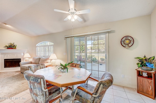 dining area featuring ceiling fan, light tile patterned flooring, a textured ceiling, and a high end fireplace