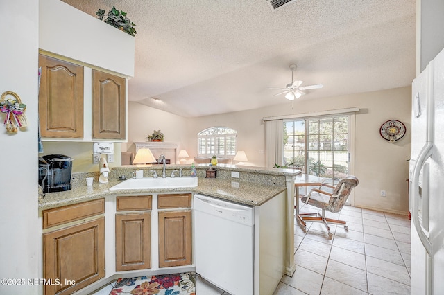 kitchen featuring lofted ceiling, a ceiling fan, a sink, white appliances, and a peninsula