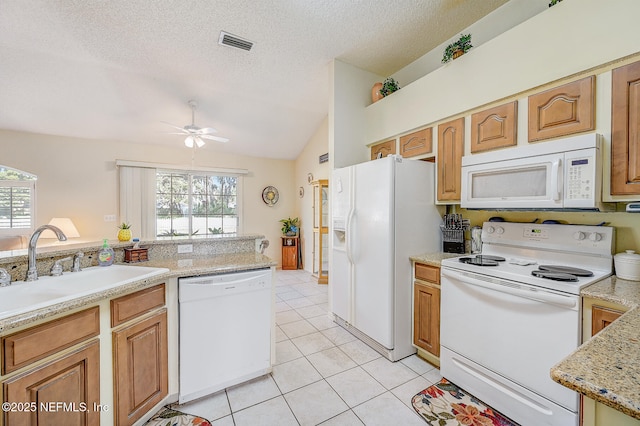 kitchen with light tile patterned floors, visible vents, vaulted ceiling, a sink, and white appliances