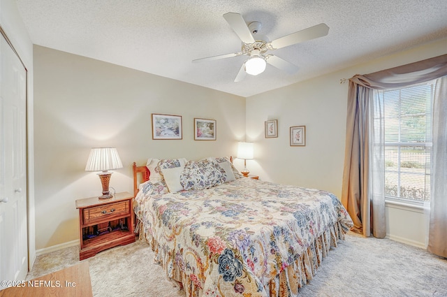 carpeted bedroom with ceiling fan, a closet, baseboards, and a textured ceiling