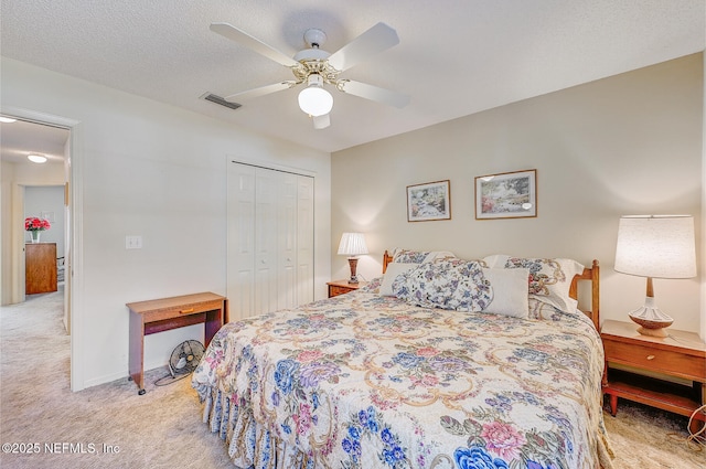 bedroom featuring a textured ceiling, ceiling fan, light colored carpet, visible vents, and a closet