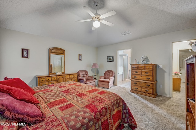 bedroom featuring visible vents, a ceiling fan, light colored carpet, ensuite bath, and a textured ceiling