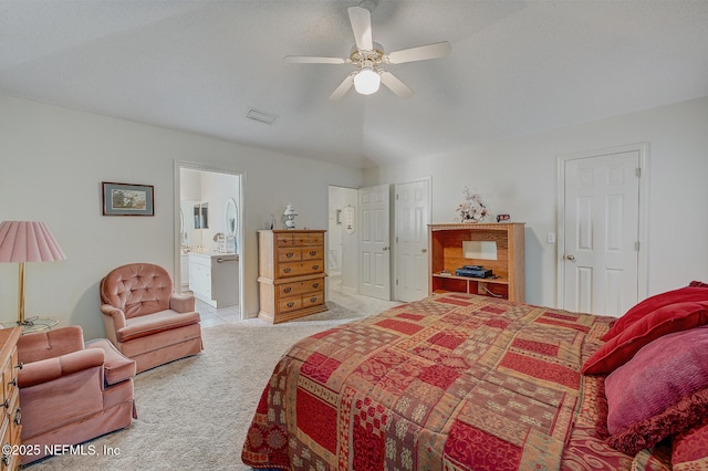 bedroom featuring a ceiling fan, ensuite bath, visible vents, and light colored carpet