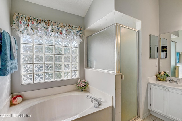 full bath with a stall shower, a garden tub, vanity, and a textured ceiling