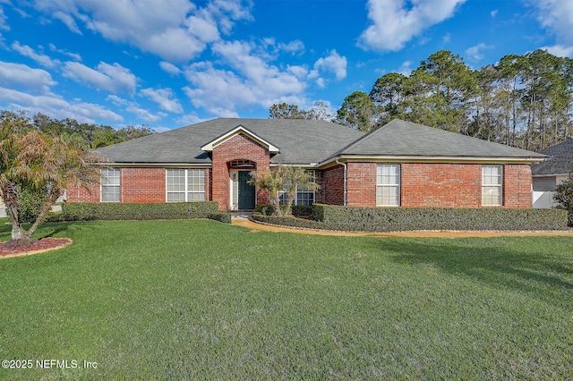 ranch-style home with brick siding, roof with shingles, and a front yard