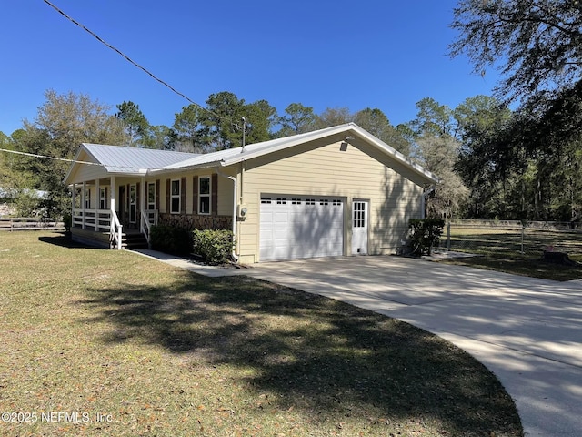 view of front facade with metal roof, covered porch, a garage, driveway, and a front yard